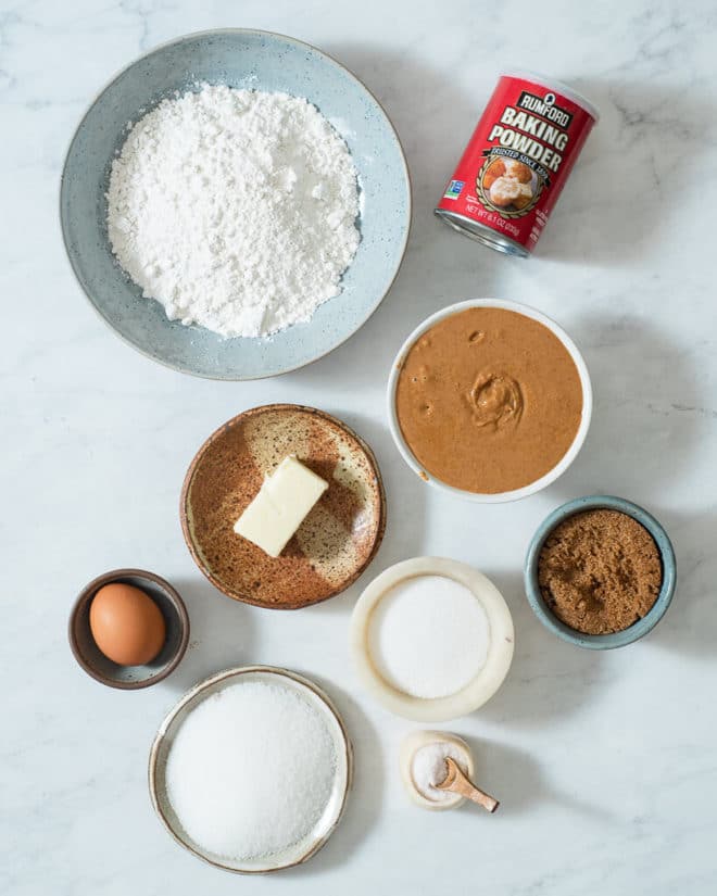 the ingredients for peanut butter cookies in different sized bowls and plates on a marble surface
