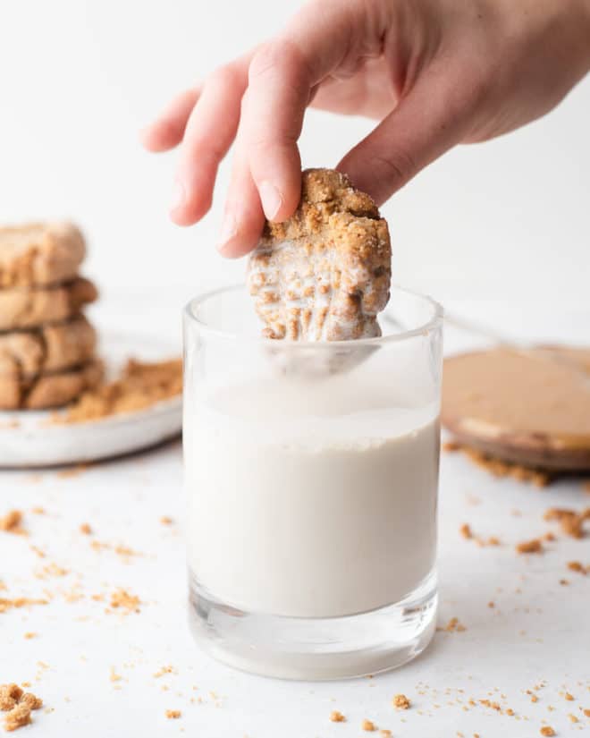 a person dippinga peanut butter cookie in a glass of milk
