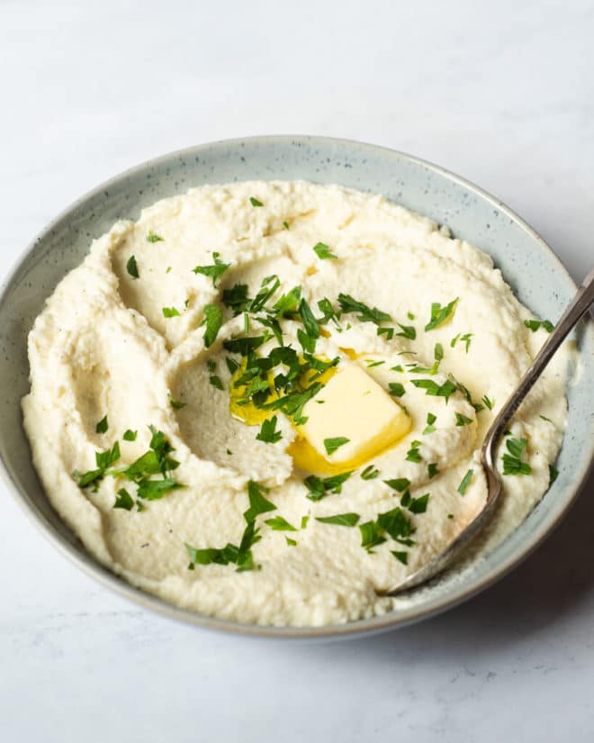 a bowl of mashed parsnips garnished with parsley and a pat of butter