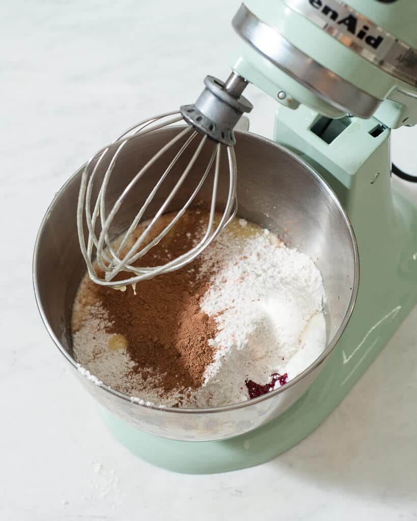 a person using a stand mixer to mix together red velvet cake batter