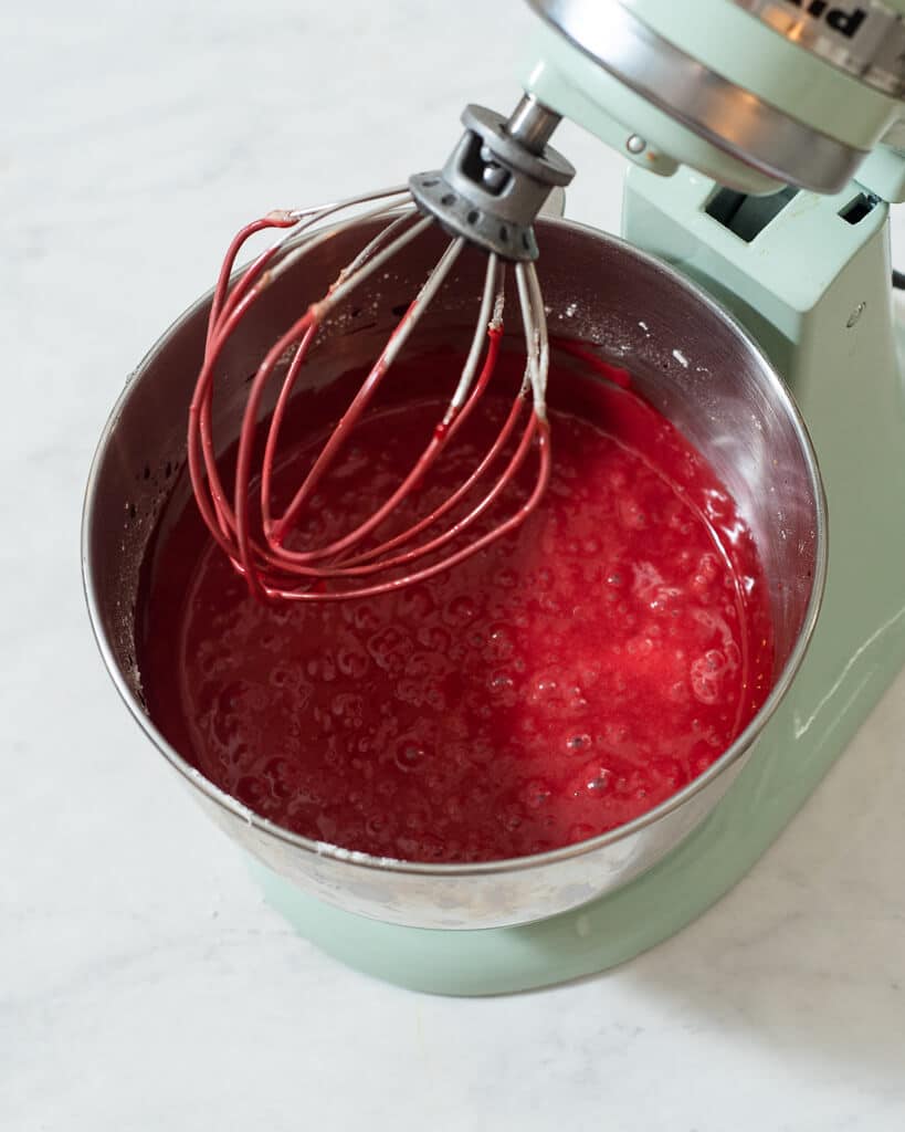 a person using a stand mixer to mix together red velvet cake batter