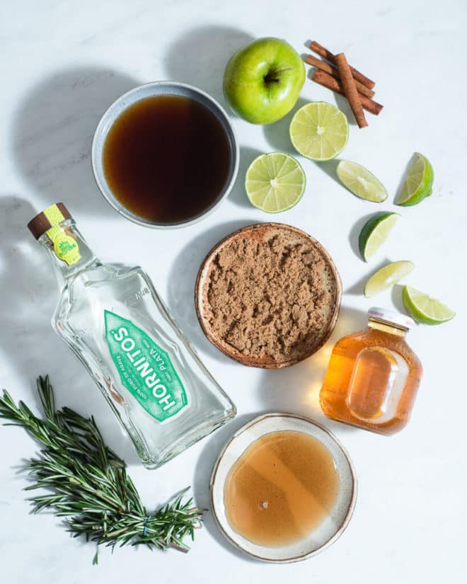 all of the ingredients for apple cider margaritas on a marble surface