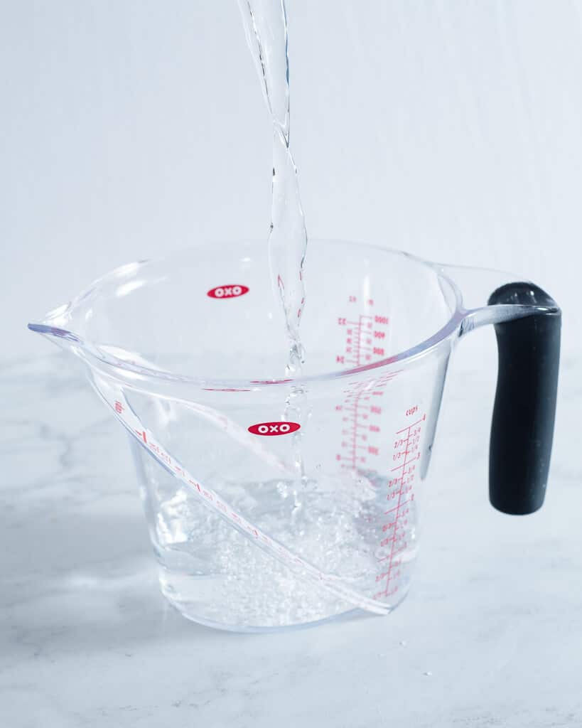 a person pouring water into a measuring cup