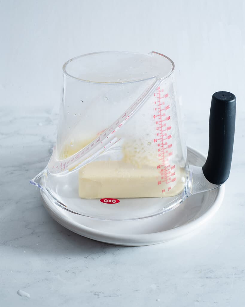 a steamy measuring cup upside down over a stick of butter