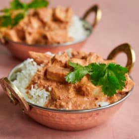 a copper bowl of Indian-inspired butter chicken over white rice