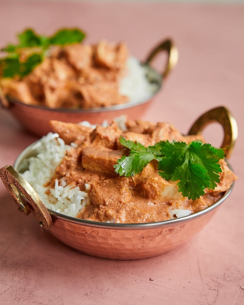 a copper bowl of Indian-inspired butter chicken over white rice