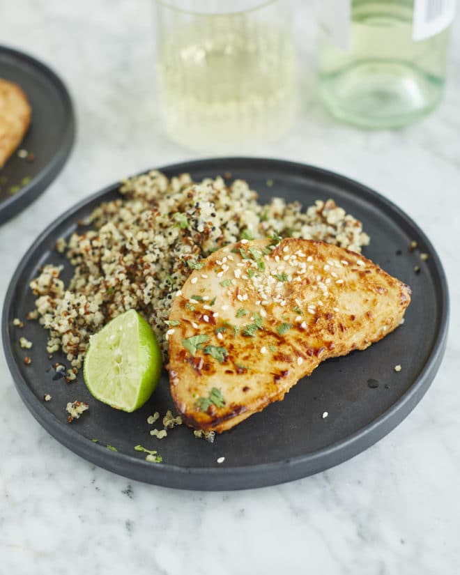 a chili lime tuna steak next to quinoa and a wedge of lime on a plate