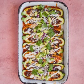 enchilada stuffed zucchini boats topped with sour cream, avocado, and cilantro