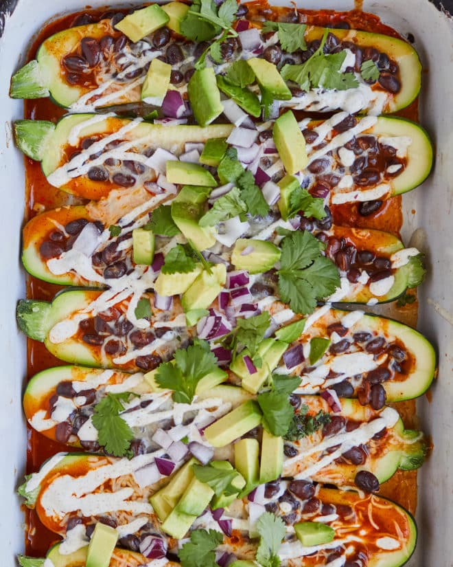 enchilada stuffed zucchini boats topped with sour cream, avocado, and cilantro