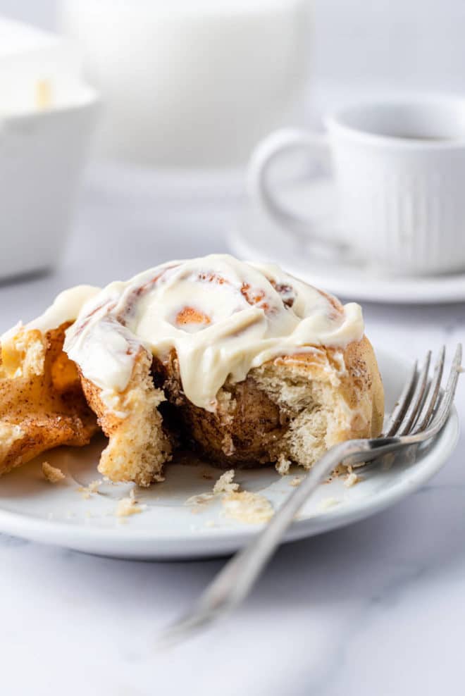 a plate with a cinnamon roll on it next to a fork
