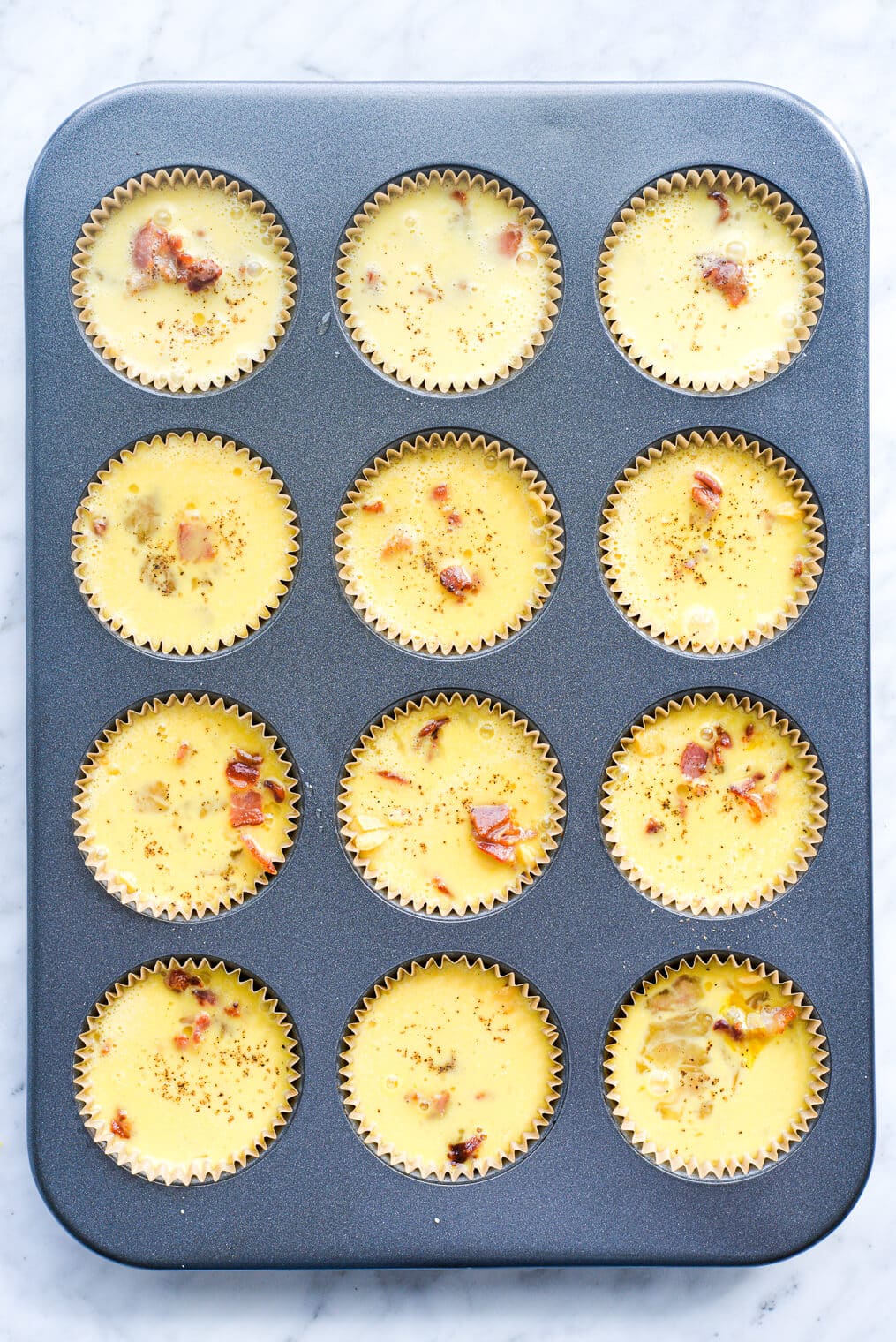 egg muffins in a muffin tin before baking in the oven