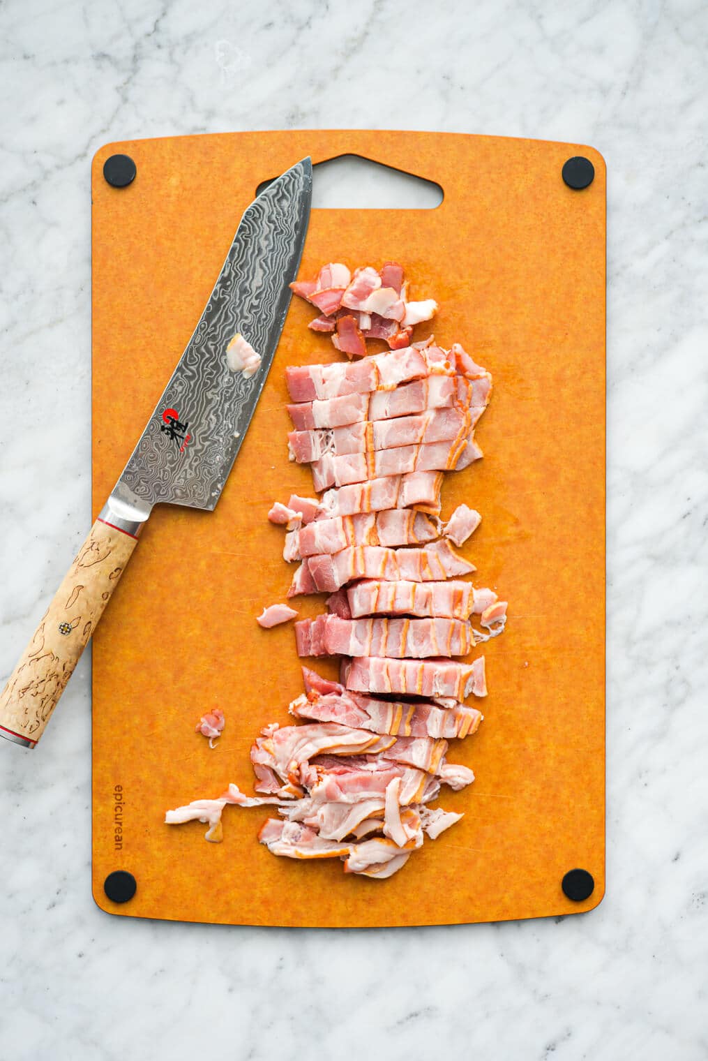 chopped bacon on a cutting board next to a large knife