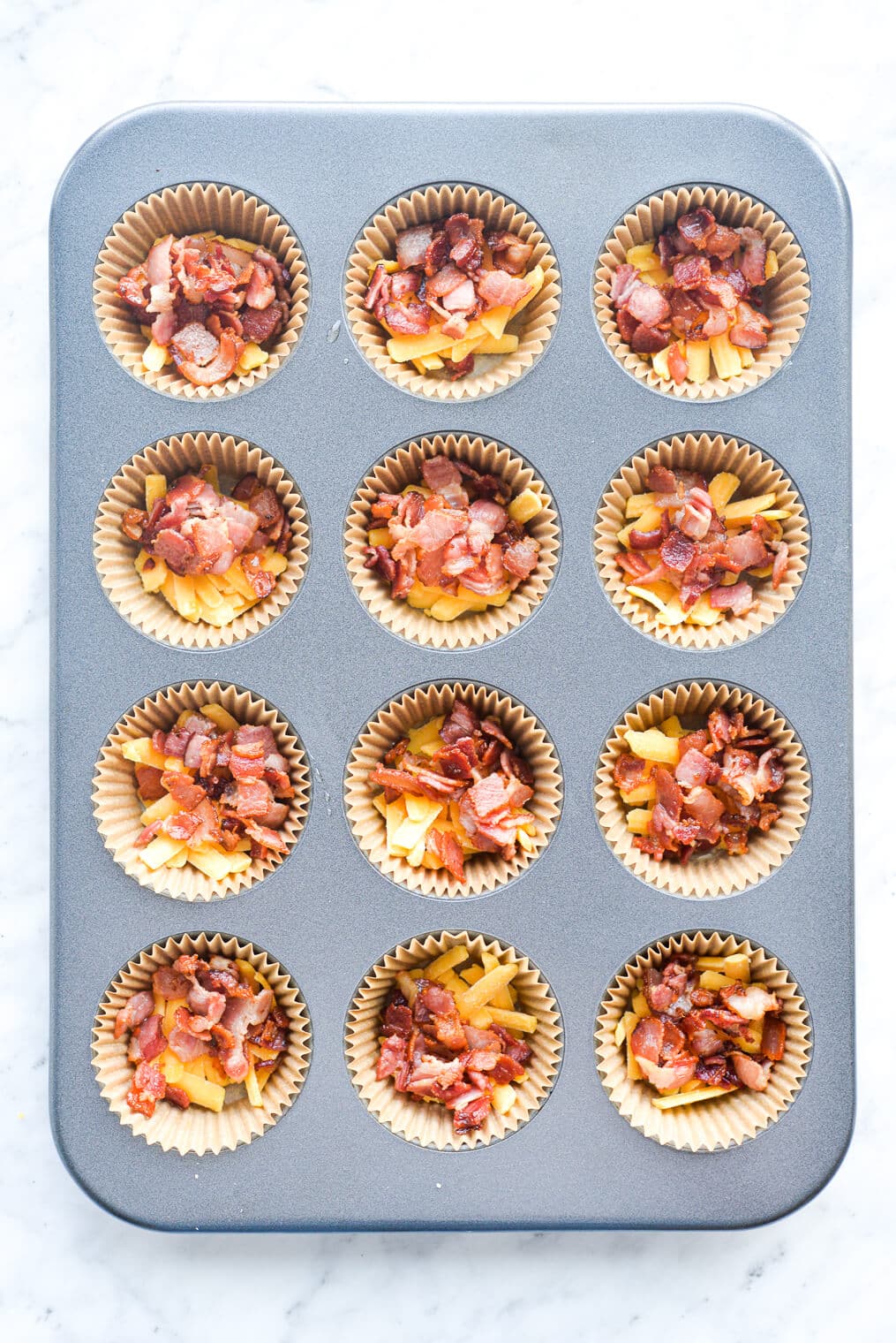 cheese and bacon in the bottom of muffin tins before eggs are added on top for egg muffins