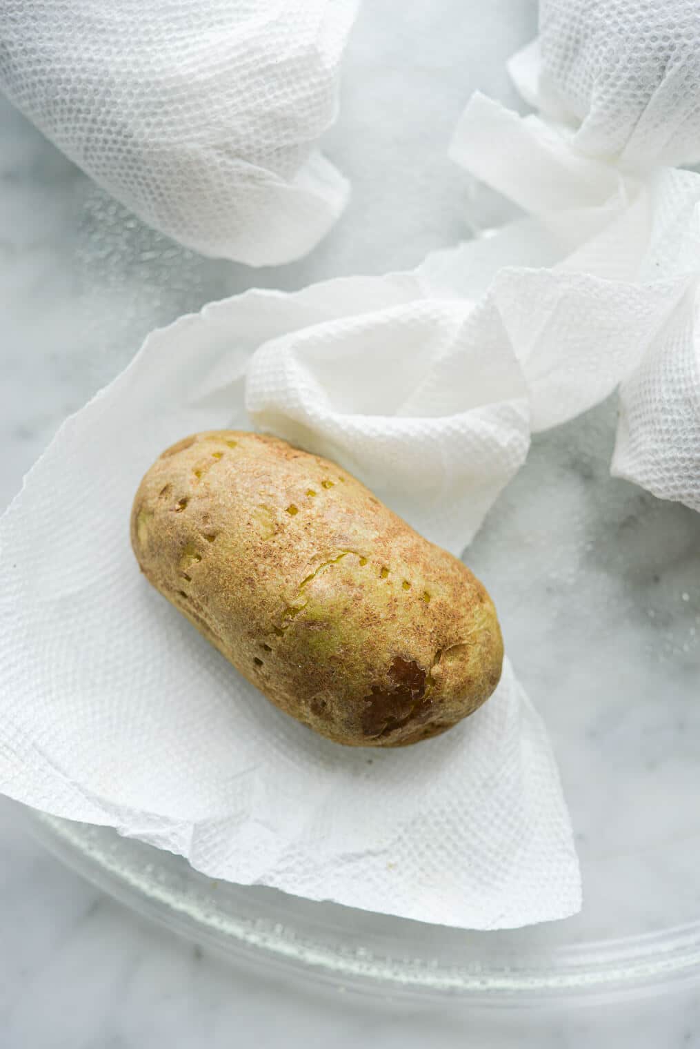 potatoes being wrapped in damp paper towels before going into the microwave