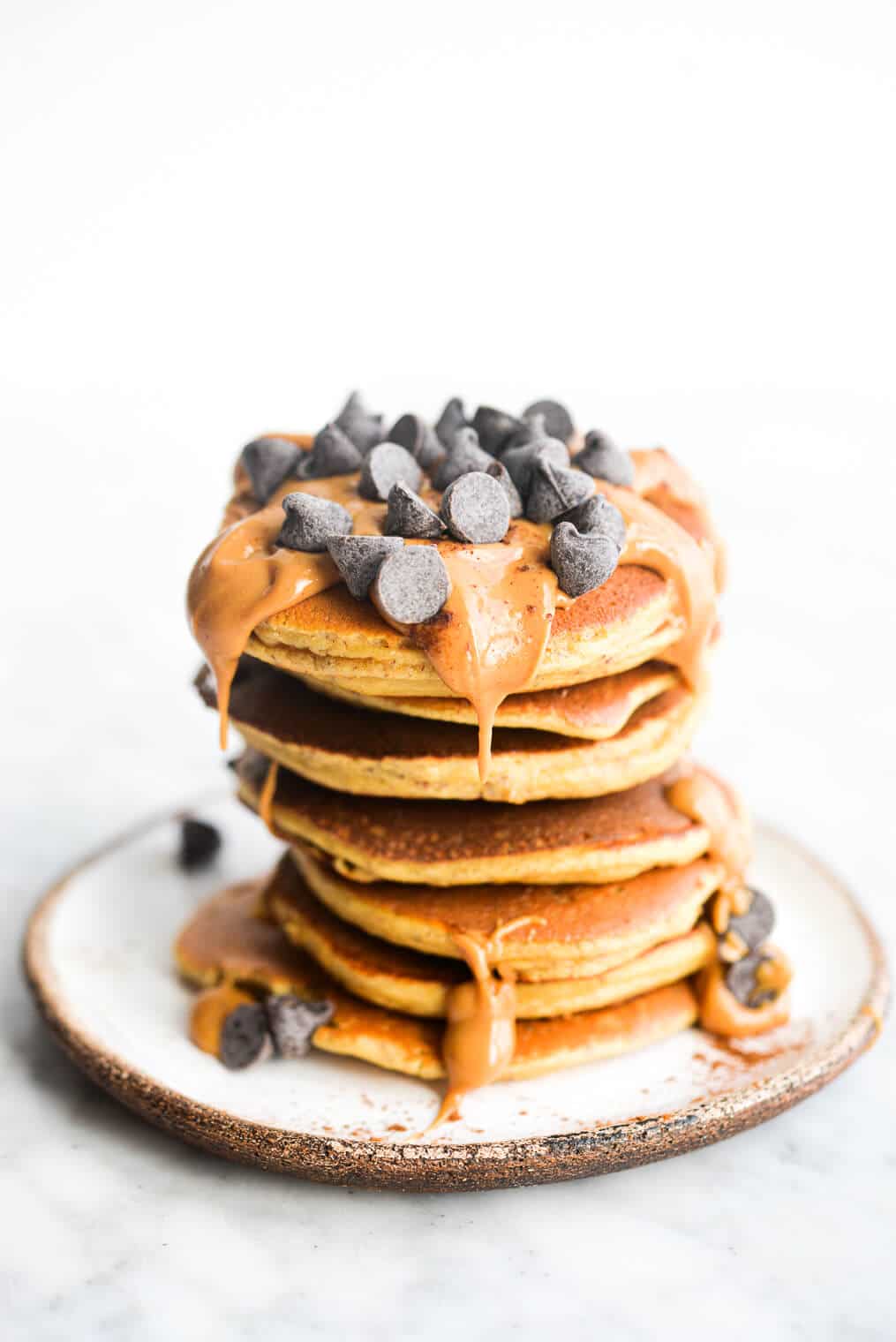 a stack of protein pancakes topped with peanut butter and chocolate chips