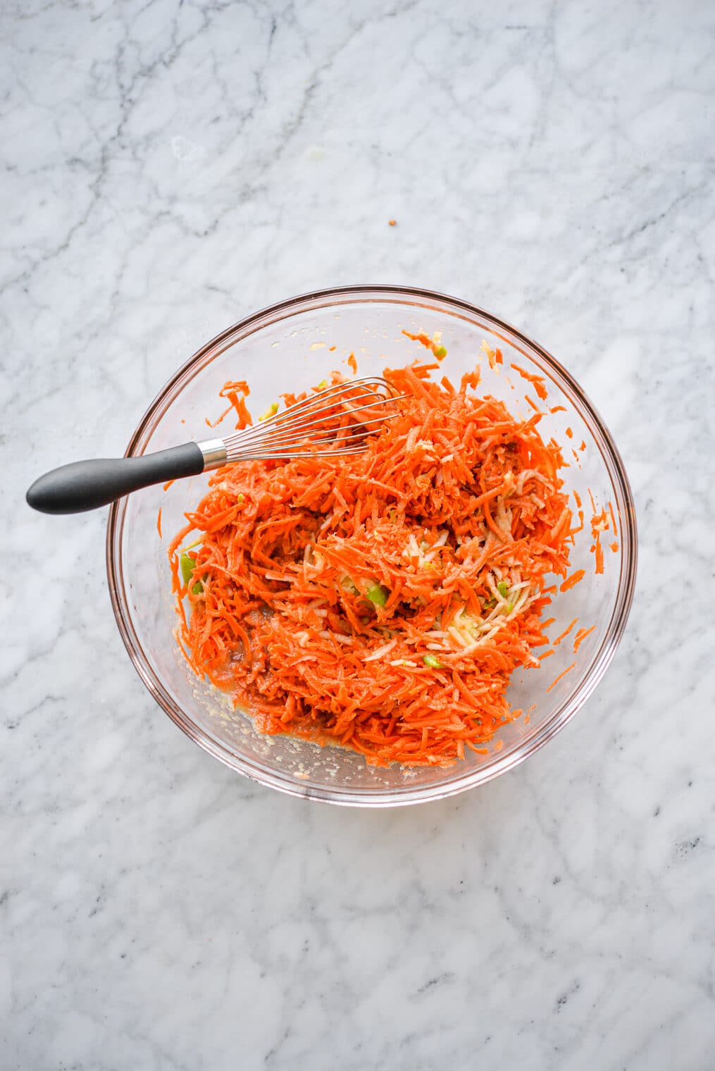 shredded carrots and apples in a large glass mixing bowl