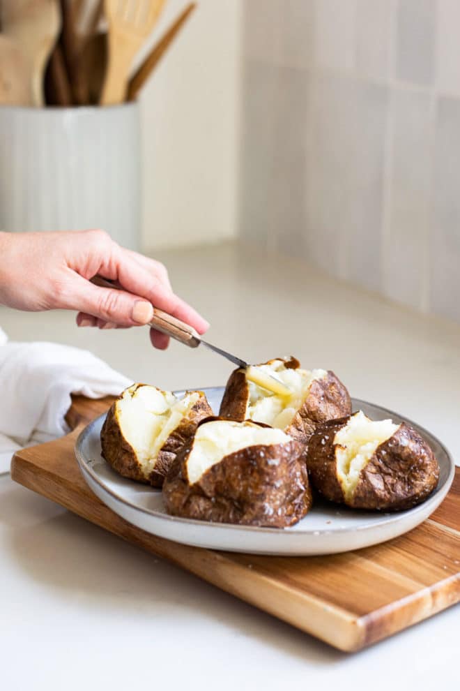 4 potatoes split in half with butter being added to them