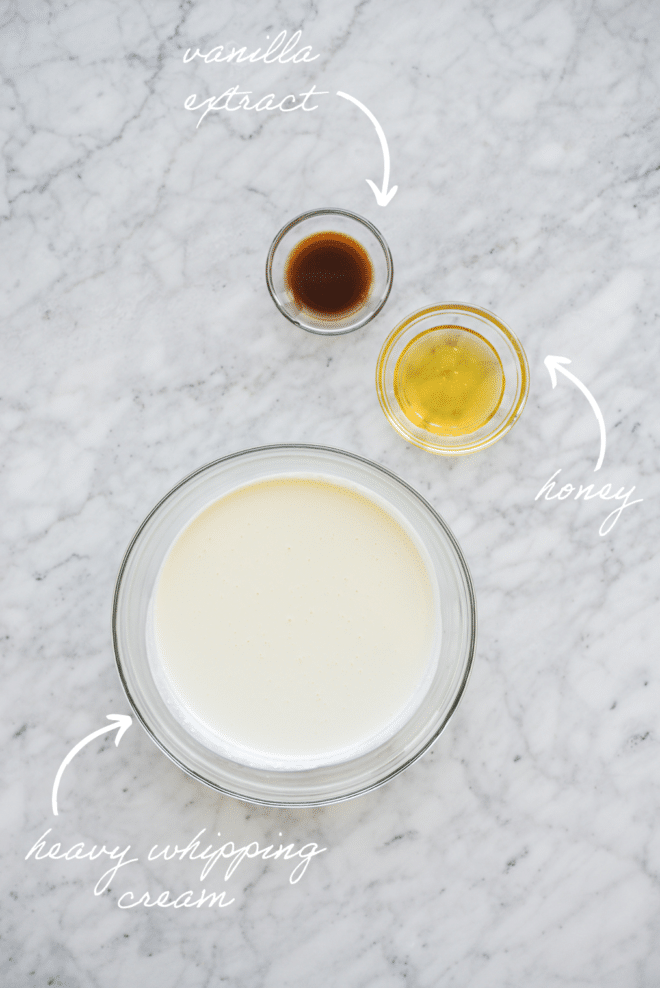 all of the ingredients for honey sweetened whipped cream in bowls on a marble surface