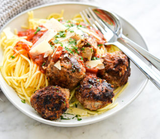 a bowl of turkey meatballs next to spaghetti noodles and red sauce