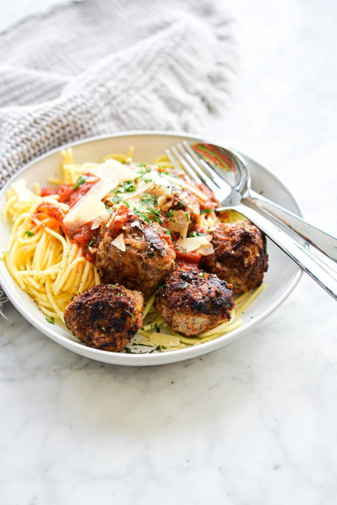 a bowl of turkey meatballs next to spaghetti noodles and red sauce