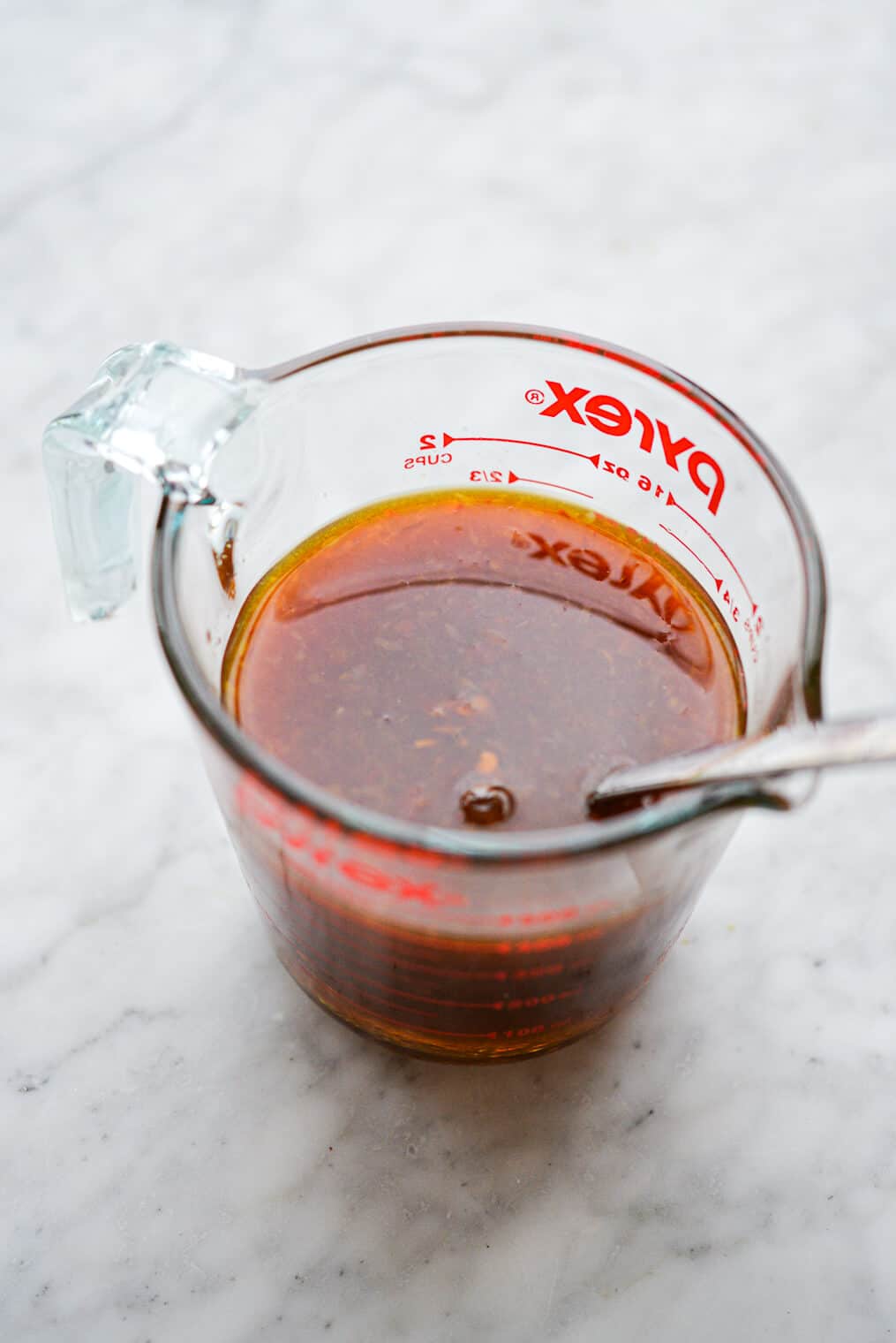 Stir fry sauce mixture in a measuring cup with silver spoon