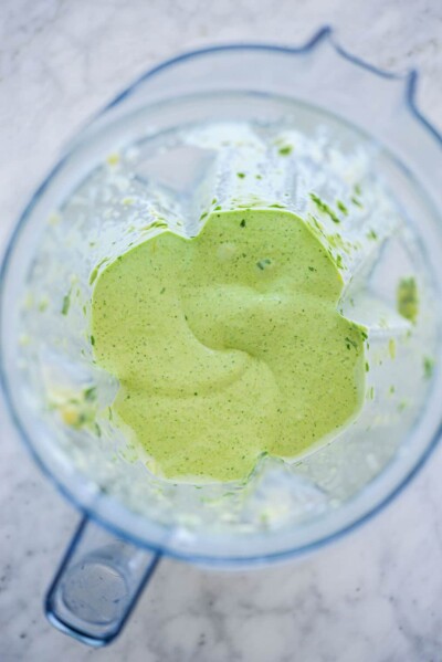 Top down view of blender with avocado smoothie ingredients blended