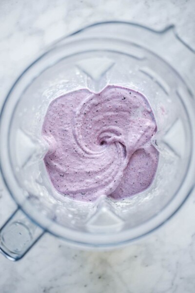 Top down view of blender with blueberry smoothie ingredients blended