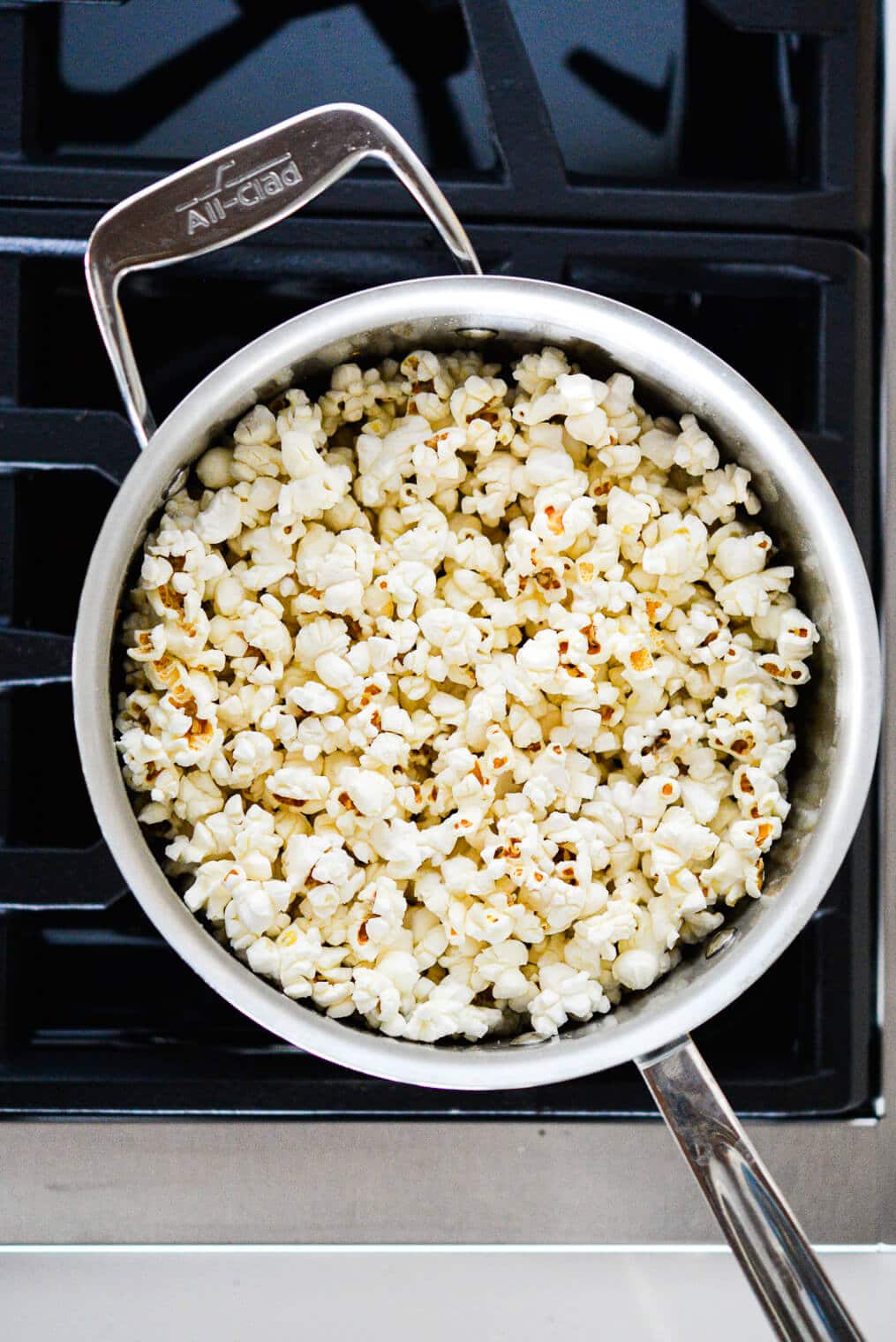 Stainless steel pot with popped corn sitting on stove top