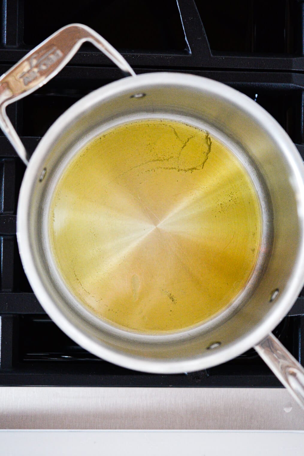 Stainless steel pot with bottom coated in oil sitting on stovetop