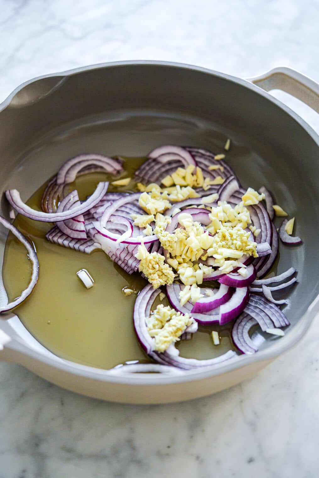 Sauté pan with sliced red onion, minced garlic, and oil