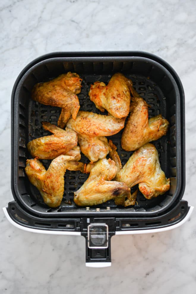 Air fryer drawer with air fried chicken wings.