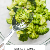 close up of silver spoon with broccoli floret and bowl of broccoli florets blurred in background, with the words, "simple steamed broccoli" in black letters on white background and the Fed + Fit logo in golden letter on the bottom