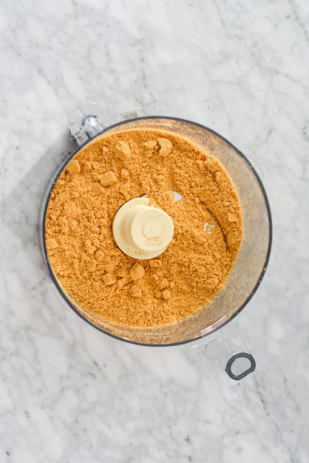 Food processor work bowl with ground graham crackers.