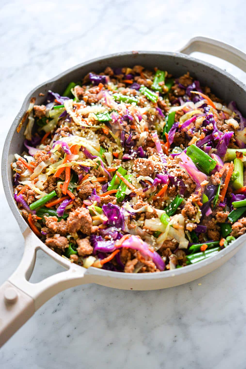 Sauté pan with egg roll in a bowl with vibrant colors of purple, orange, and green.