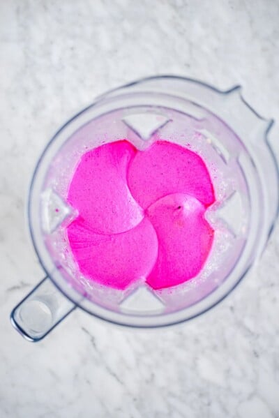 Bright magenta smoothie ingredients blended in a blender.