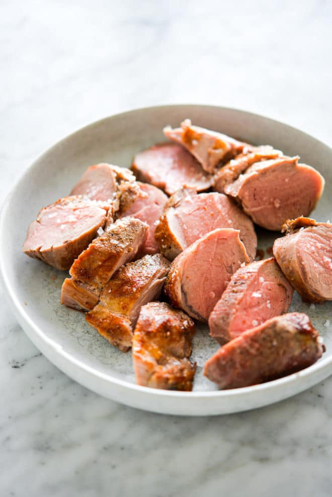 Pork tenderloin slices on a light grey plate.