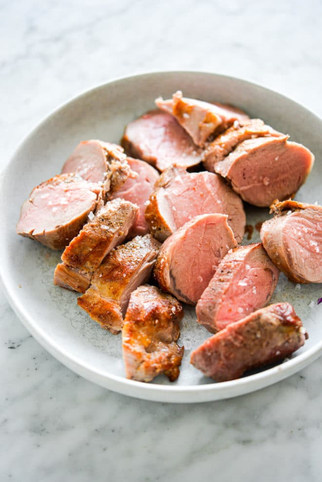 Pork tenderloin slices on a light grey plate.
