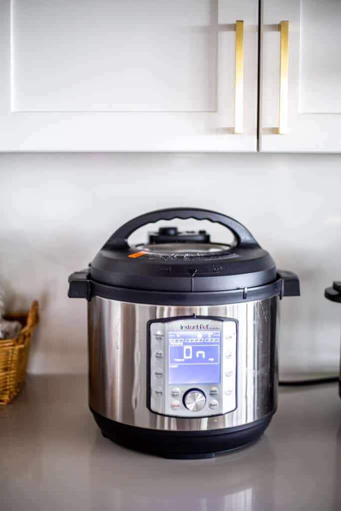 Instant pot sitting on countertop in the "on" position.