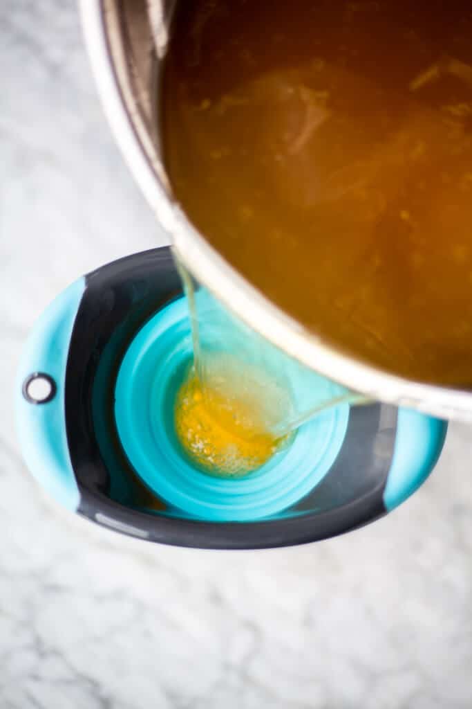Broth being poured into a turquoise and black silicone funnel.