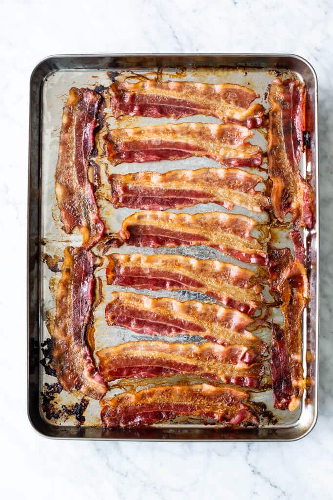 Sheet pan with baked bacon in a single layer.