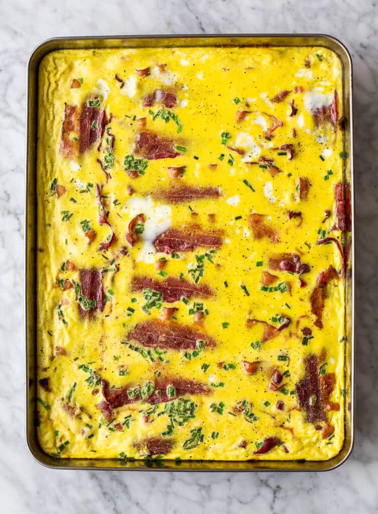 Sheet pan with bacon, baked eggs, and chives.