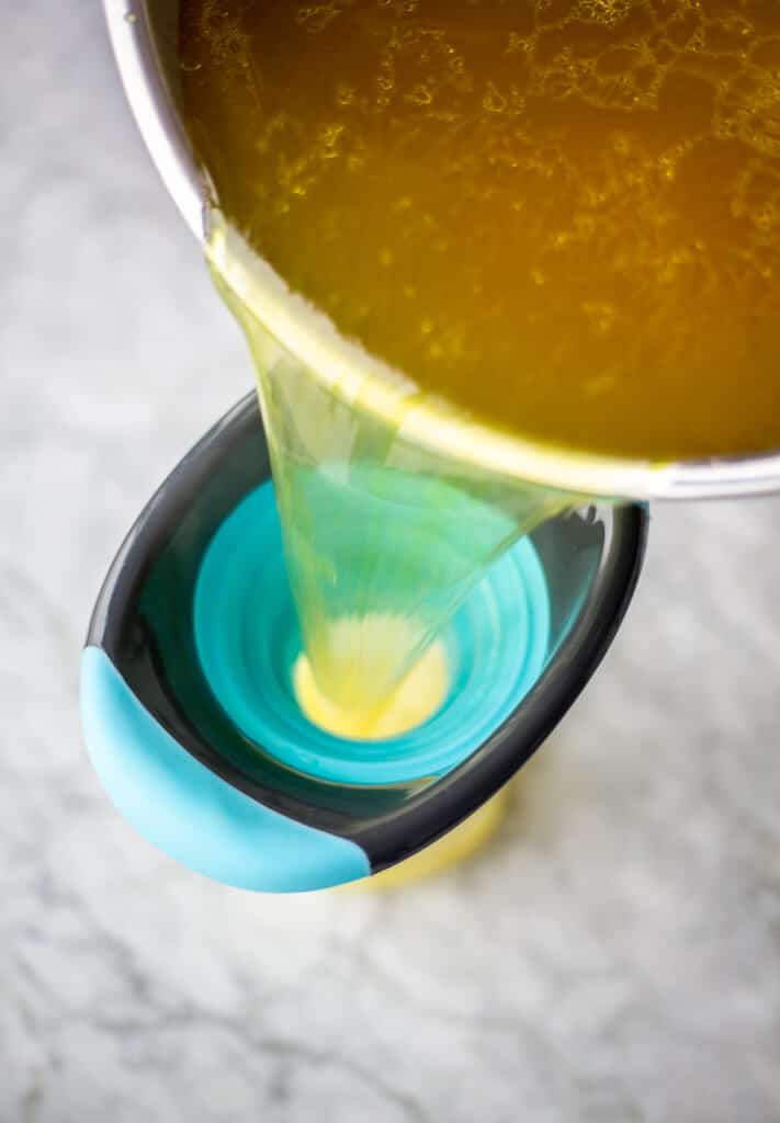 Broth being poured into a turquoise and black silicone funnel.