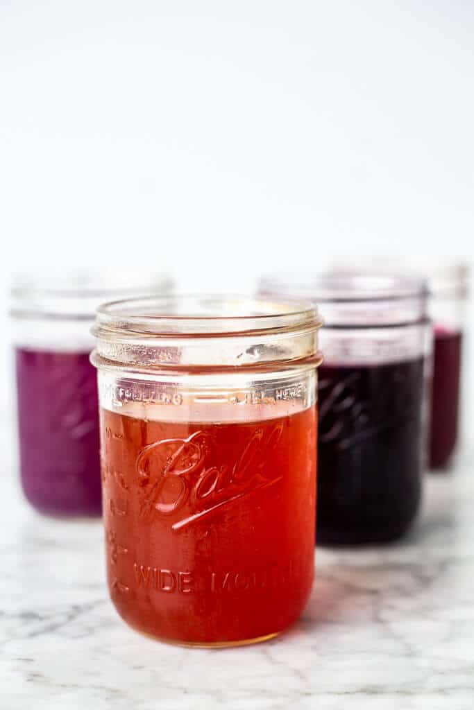 Glass mason jars with multiple colors of liquid.