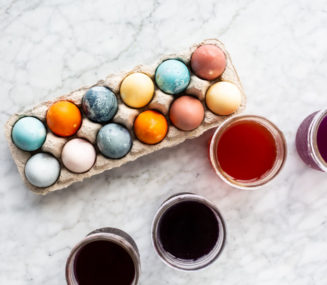 Top down view of egg carton with multi-colored eggs and 4 mason jars with colored liquid inside.