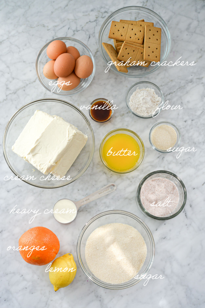 Top down shot of classic cheesecake ingredients with ingredient labels written out in white, cursive letters.