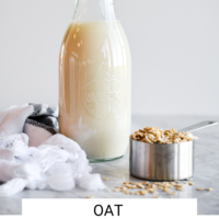 Jug of oat milk and measuring cup with dry oats on a marble countertop with the words "Oat Milk" written in black underneath and "Fed + Fit" in golden orange.