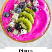 Top down view of pitaya smoothie bowl topped with blueberries, sliced kiwi, and cubed dragon fruit with the words "Pitaya Smoothie Bowl" written in black underneath and "Fed + Fit" in golden orange.