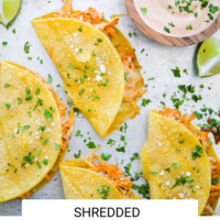 Chicken tacos on a sheet pan with dipping sauce with the words "Shredded Chicken Tacos" written in black underneath and "Fed + Fit" in golden orange.