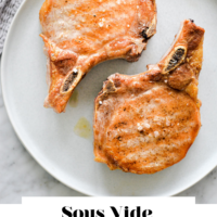 Two, cooked, bone-in pork chops on a round plate with the words "Sous Vide Pork Chop" written in black underneath and "Fed + Fit" in golden orange.