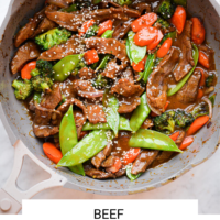 Sauté pan with beef stir dry with the words "beef stir fry" on the bottom written in black letters and "Fed & Fit" in golden orange letters.